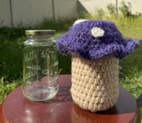 a crocheted mushroom next to a mason jar