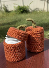 two crocheted pumpkin jars on a table